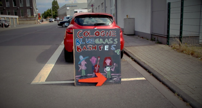 Ein Schild auf der Straße, das zum Cologne Bluegrass Bashfest weist